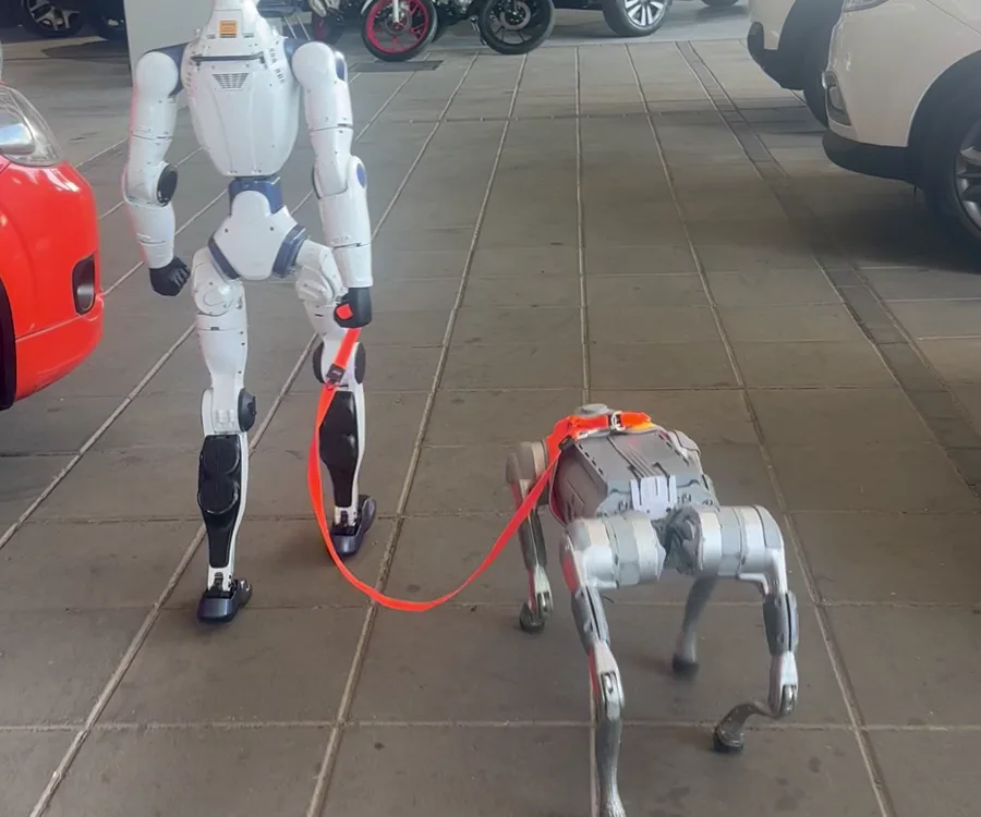 Robô humanoide R1 caminhando com o cão robô Go2 Pro na guia, em ativação da RoboFaz
