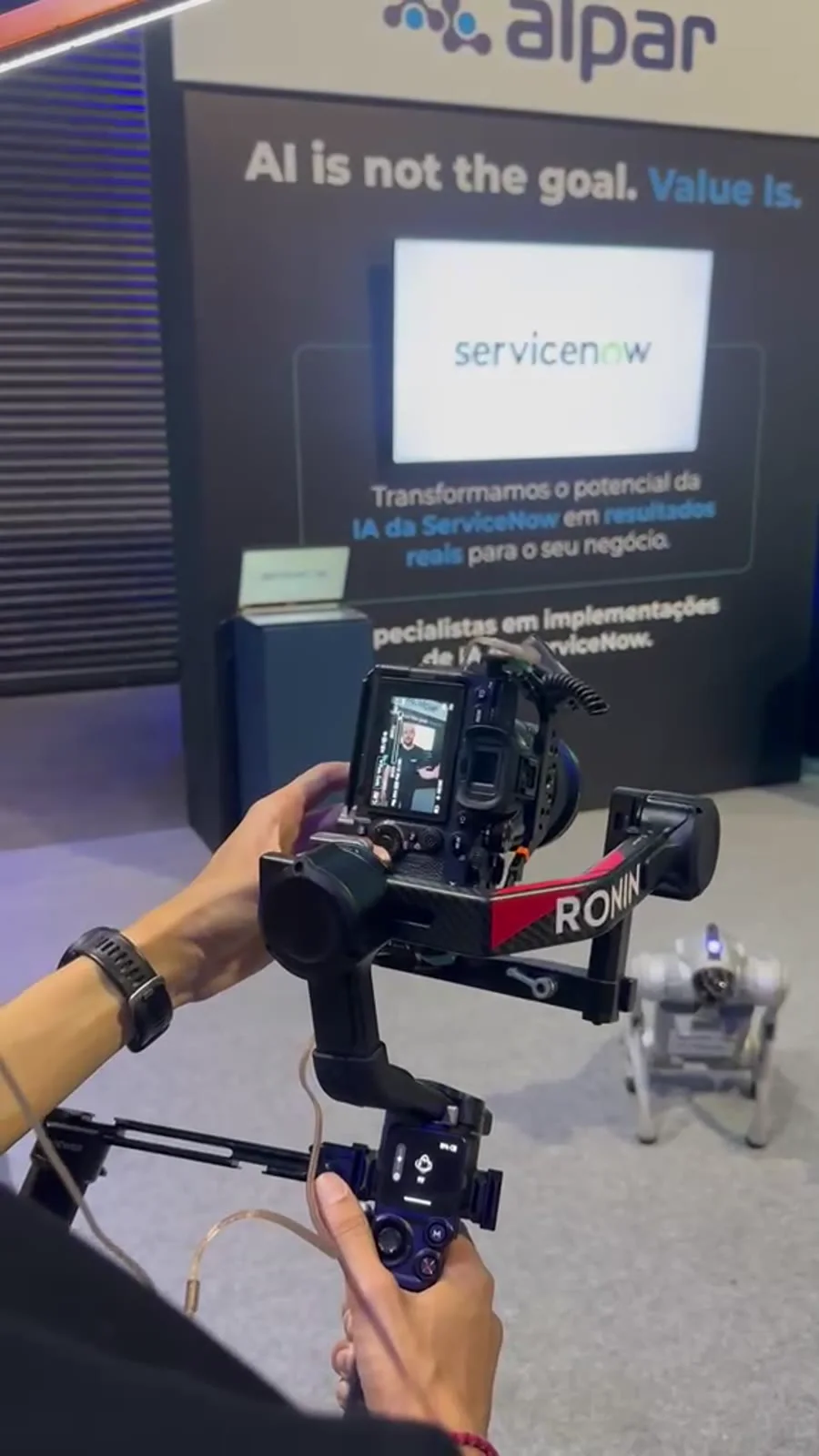 Cão robô Go2 Pro sendo filmado com câmera profissional em evento da Alpar sobre ServiceNow