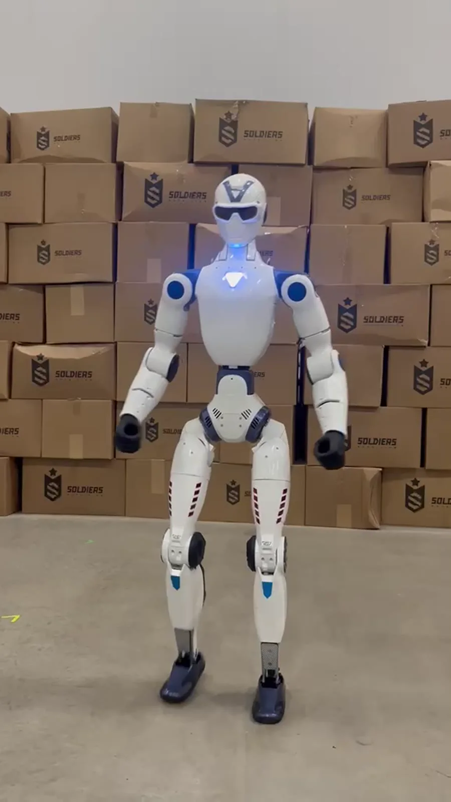 Robô humanoide R1 nos bastidores, em frente a caixas com a marca Soldiers, antes de se apresentar